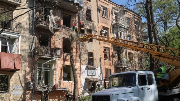 Komunální pracovníci pracují na staveništi u obytného domu poškozeného ruským náletem uprostřed ruského útoku na Ukrajinu.