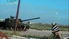 Protivládní demonstrant hází kámen na projíždějící tank v místě Dará