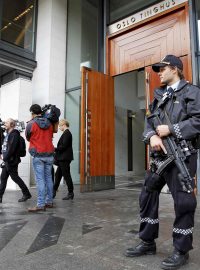 Novináři a ozbrojený policista před budovou soudního dvora v Oslu během stání s Breivikem