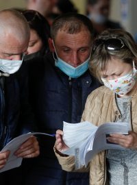 Ukrajinští pracovníci studují dokumenty před cestou do Polska